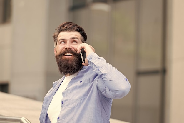 Gut aussehender Mann mit Borsten im Freien Mann mit Freizeithemd hält Smartphone Modernes Leben Agiles Geschäft Danke Wie geht es Ihnen Mobile Kommunikation Geschäftsgespräch Mann mit Smartphone