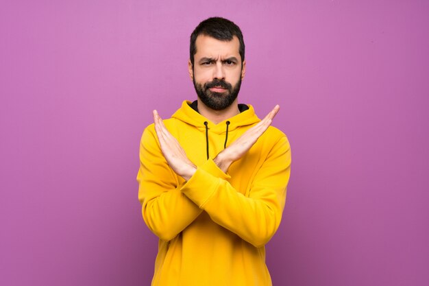 Gut aussehender Mann mit dem gelben Sweatshirt, das KEINE Geste macht