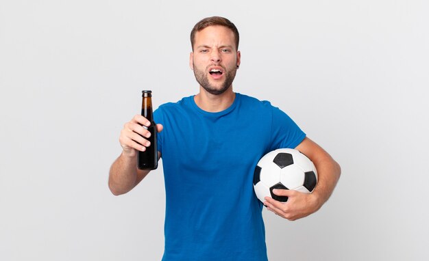 Gut aussehender Mann mit einem Bier und einem Fußball