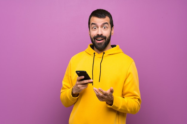 Gut aussehender Mann mit gelbem Sweatshirt überraschte und eine Mitteilung sendend