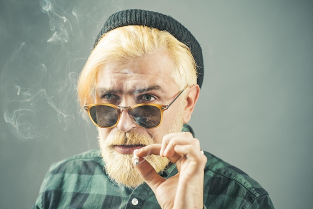 Gut aussehender Mann mit großem Lächeln, der eine Modebrille vor dunklem Hintergrund mit Kopienraum trägt