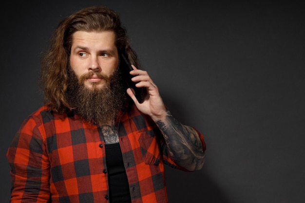 Gut aussehender Mann mit langen Haaren, der ein Handy am Ohr hält.