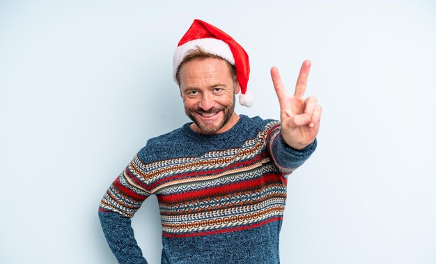 Gut aussehender Mann mittleren Alters, der lächelt und glücklich aussieht und Sieg oder Frieden gestikuliert. Weihnachtskonzept