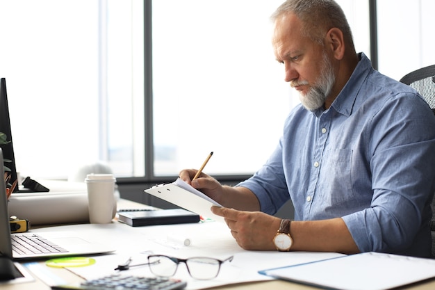 Gut aussehender reifer Architekt, der etwas während der Arbeit im Büro zeichnet.