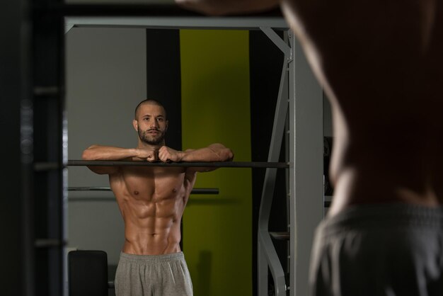 Foto gut aussehender und attraktiver junger mann mit muskulösem körper, der sich im fitnessstudio entspannt