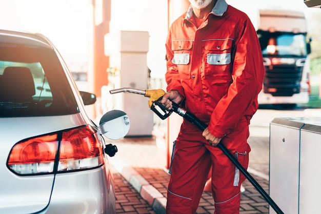 Gutaussehender älterer Bartmann, der an einer Tankstelle arbeitet.