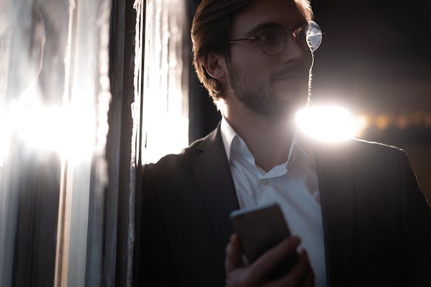 Gutaussehender junger Mann mit Smartphone in der Nacht Nahaufnahme des glücklichen Geschäftsmannes, der nachts im Café Nachrichten auf dem Handy sendet