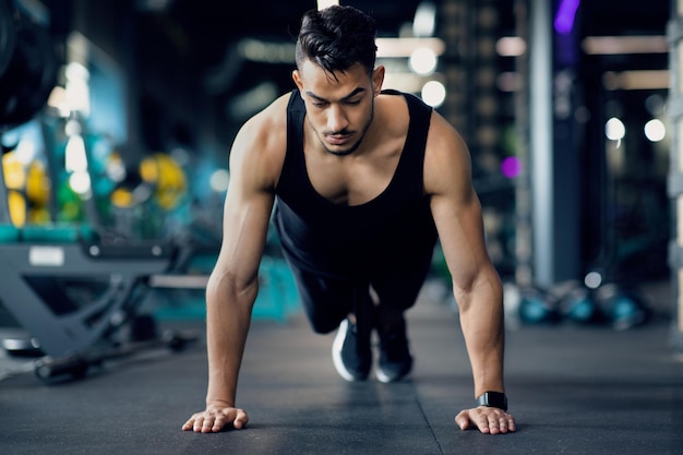 Gutaussehender Mann aus dem Nahen Osten, der im Fitnessstudio Liegestützübungen auf dem Boden macht