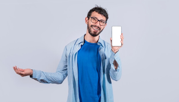 Gutaussehender Mann, der positiv lächelt und den leeren Bildschirm des Mobiltelefons mit einer anderen Handfläche offen zeigt, aufgeregt, glücklicher Mann, der Smartphone hält