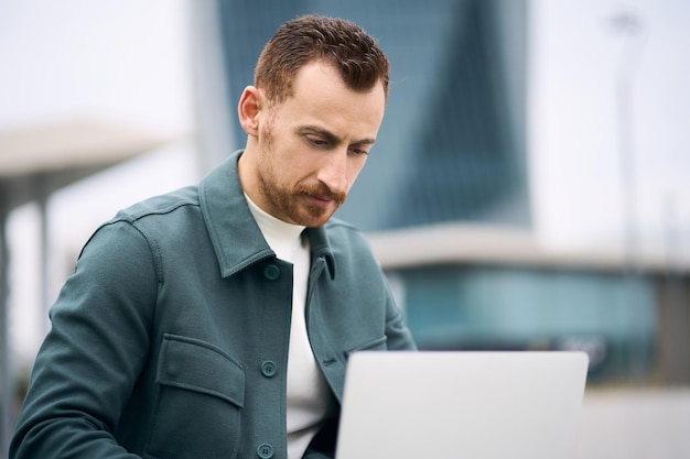 Gutaussehender Programmierer mit Laptop-Computer, der an einem freiberuflichen Projekt am Arbeitsplatz arbeitet