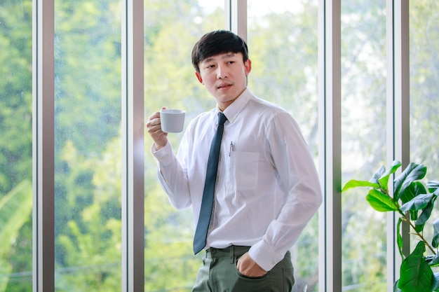 Gutaussehender und kluger Geschäftsmann genießt es, eine Tasse Kaffee zu trinken, um das Gehirn während der fröhlichen Pausen zur Erfrischung zu entspannen und eine kreative Idee für das professionelle Management im Firmenbüro zu erwägen