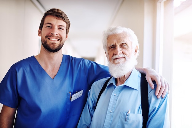 Gute Gesundheit zaubert jedem ein Lächeln ins Gesicht Porträt eines jungen Arztes und seines älteren Patienten, die gemeinsam im Krankenhaus posieren