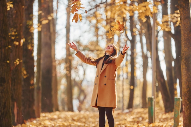 Gute Laune haben Frau im Mantel hat einen Spaziergang im Herbstwald