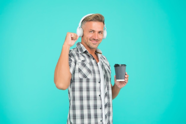 Gute laune. stressresistenz-konzept. kerl, der musikkopfhörer hört und kaffee trinkt. normaler morgen. motivierende musik. reifer mann genießt perfekten inspirierenden kaffee und gesang. kaffee zum mitnehmen.