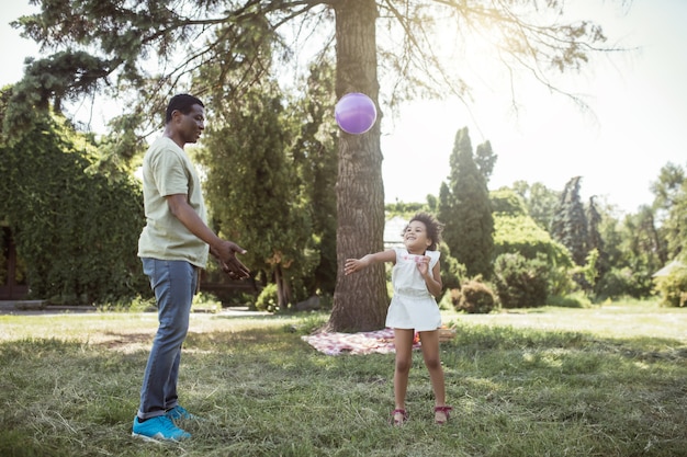 Gute Zeit. Mann und sein süßes Kind spielen Ball im Park