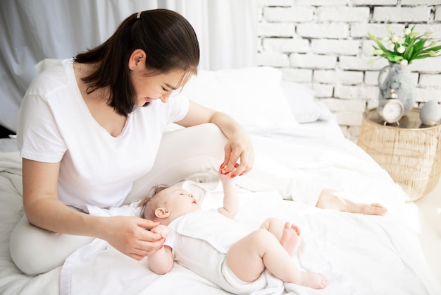 Guten Morgen im Schlafzimmer der Familie. Mama hält die Hände ihres Babys