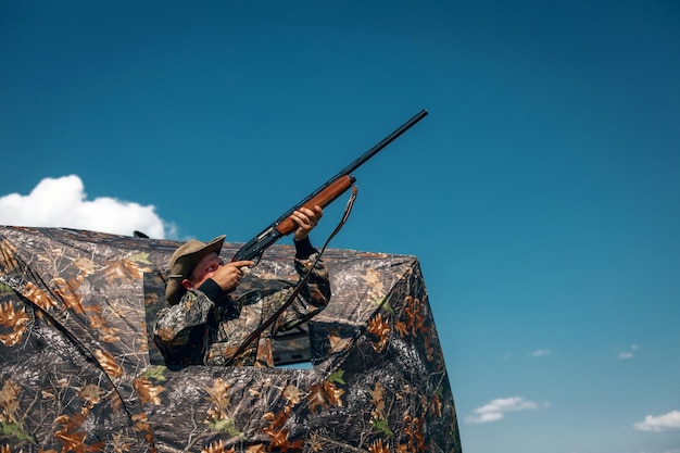 Guter Schuss, der im Khaki-Zelt im Hinterhalt steht und in den Himmel zielt; Jäger Konzept.