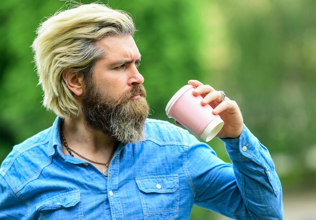 Guter Start in den Morgen Mann mit einer Tasse Kaffee im Freien Schöner ruhiger bärtiger Mann im Freien mit einer Tasse Kaffee Mann trinkt heißen Kaffee Tourist entspannt im Park Tee trinken Kaffee für unterwegs