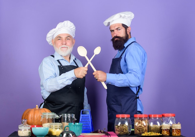 Gutes Team Müsli und Würze professioneller Restaurantkoch Halloween-Kürbisrezept Chefkoch, der fröhliche Männer kocht, bereiten Essen zu Ältere, bärtige Männer in der Küche Gesundes Essen kochen