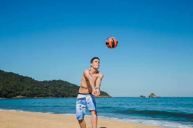 Foto guy atingindo voleibol na praia