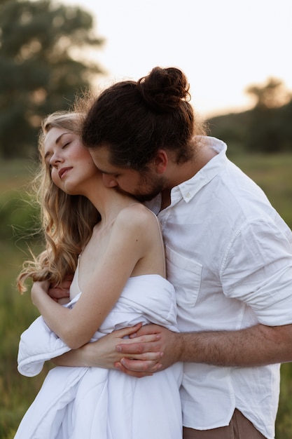 Guy besa a su novia en el cuello con una manta en la naturaleza