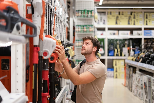 Guy de compras en la tienda de herramientas eléctricas