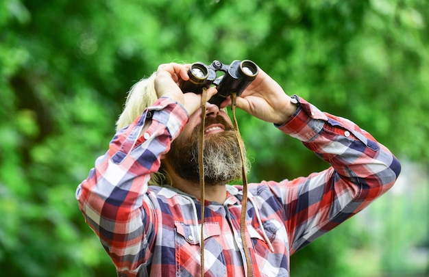 Guy explore el medio ambiente Turismo vacaciones de verano Hobby y ocio Observación de la naturaleza Expedición de ornitología del hombre en el bosque Hombre observando la naturaleza Turista hipster sostiene binoculares fondo de naturaleza