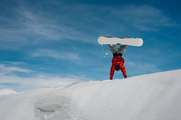 Guy está parado sobre sus manos en la nieve contra un cielo azul de invierno