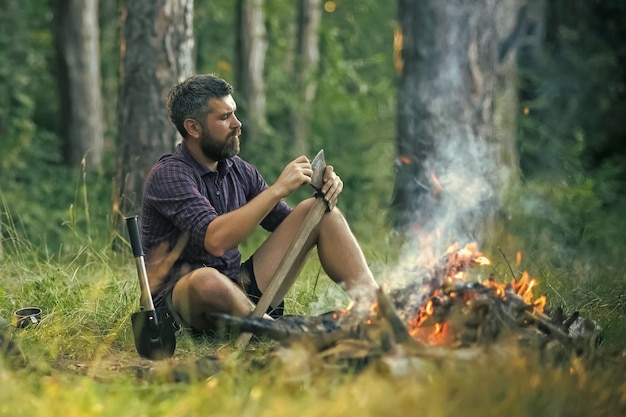 Guy relajarse en la hoguera en el bosque.