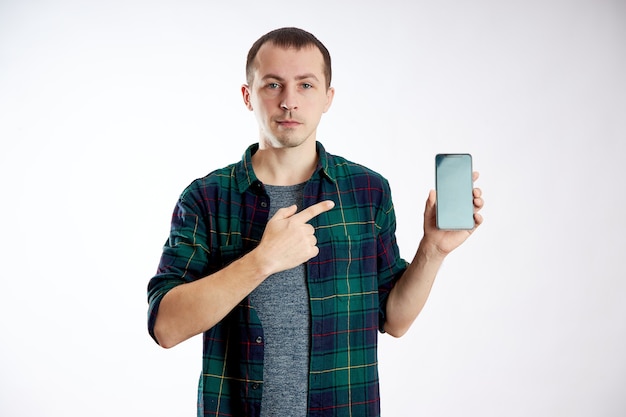 Foto guy segura o telefone nas mãos e aponta para ele com o dedo. um homem joga em seu telefone e assiste a vídeos, redes sociais