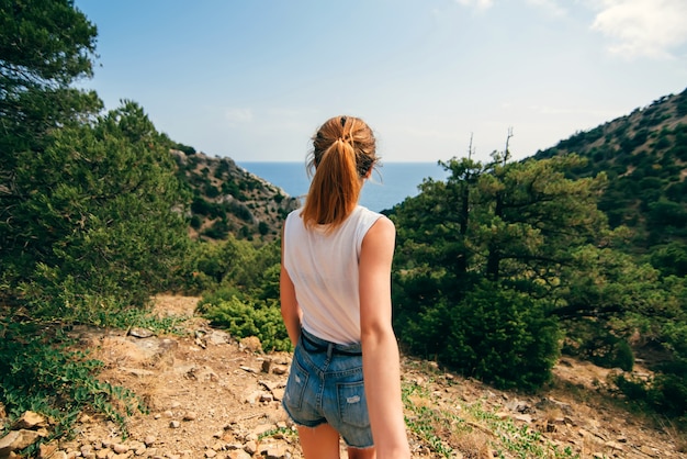 Guy sigue a su novia sosteniendo su mano en el viaje peatonal al aire libre en las montañas