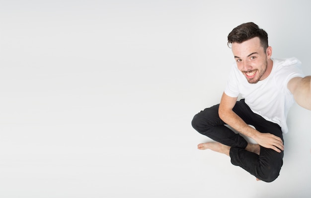 Guy sitzt auf dem Boden und macht Selfie alleine