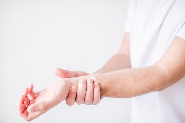 Foto guy sostiene su mano por la muñeca debido al dolor y al dolor