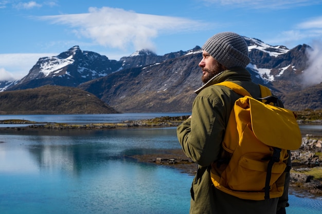 Guy viaja com uma mochila amarela por lugares pitorescos com belas paisagens montanhosas.