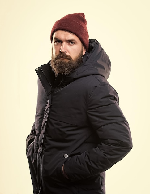 Guy Wear Hut und schwarze Winterjacke Hipster Style Menswear Hipster Outfit Mann bärtiger Hipster posiert selbstbewusst in warmer schwarzer Jacke oder Parka Stilvolle und bequeme Hipster moderne Mode