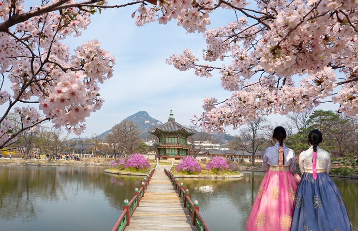Foto gyeongbokgung palace hyangwonjeong pavilion, com vestido nacional coreano e flor de cerejas na primavera, seul, coreia do sul.