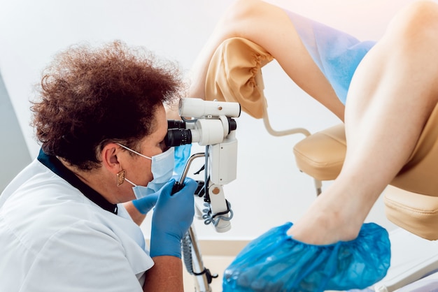 Gynäkologe, der einen Patienten mit einem Mikroskop untersucht.