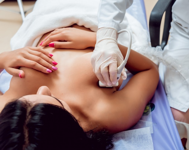 Gynäkologin führt Brustuntersuchung für ihre Patientin mit Ultraschallscanner durch