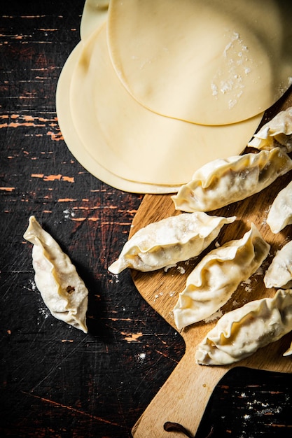 Gyoza de albóndigas crudas en una tabla de cortar de madera