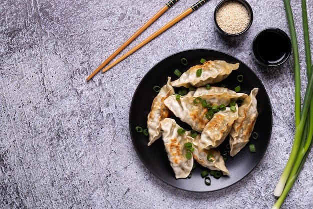 Gyoza con albóndigas fritas en un plato sobre un fondo de hormigón gris