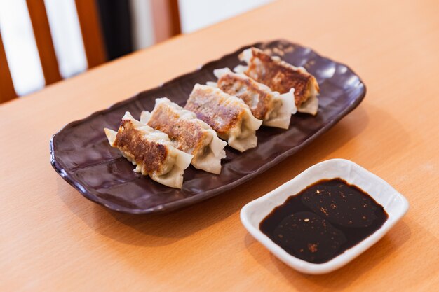 Gyoza (japanische gebratene Teigtaschen) serviert mit Sauce und Sesamöl.