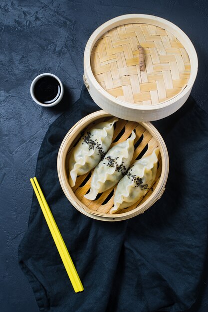 Gyoza japonesa en una vaporera tradicional, palillos amarillos.