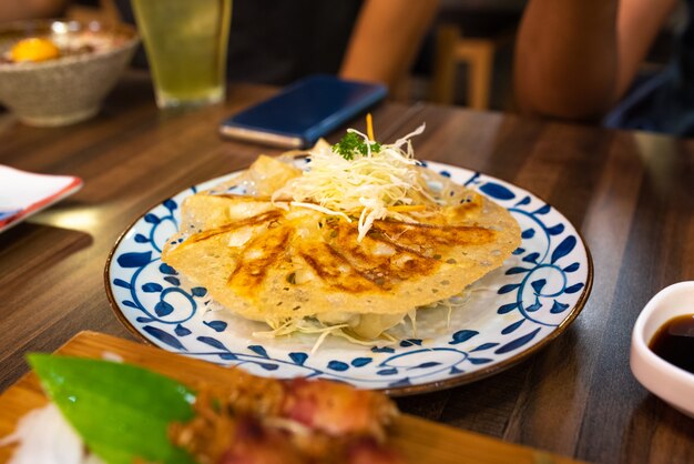 Gyoza o jiaozi frito en la placa en la tabla de madera en restaurante japonés.