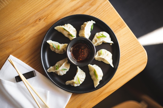 Gyoza en plato oscuro y mesa de madera.