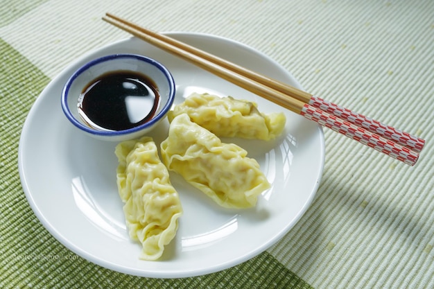 Foto gyoza con salsa se coloca en un plato blanco.