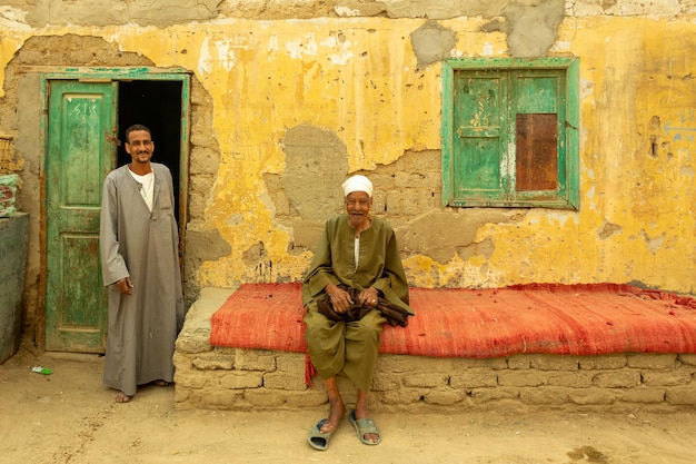 Ägyptische Männer, die traditionelle Kleidung nahe ihrem alten Haus tragen