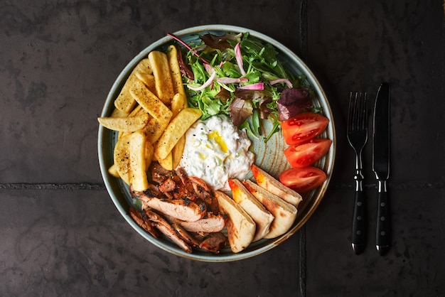 Gyros griegos con pollo o ternera con tzatziki sobre un fondo oscuro