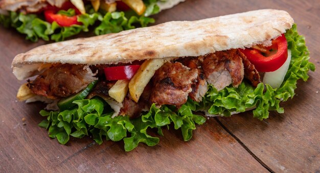 Gyros Shawarma zum Mitnehmen Street Food Sandwich mit Fleisch auf Holztisch