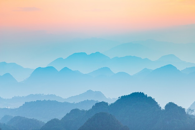 Ha Giang Karst Geopark Landschaft in Nordvietnam. Bergschattenbild atemberaubender Landschaftsnebel und Nebel in den Tälern bei Sonnenuntergang. Ha Giang Motorradschleife, berühmte Reiseziel Biker einfache Fahrer.