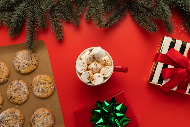 Há uma xícara de chocolate quente e biscoitos de natal na mesa